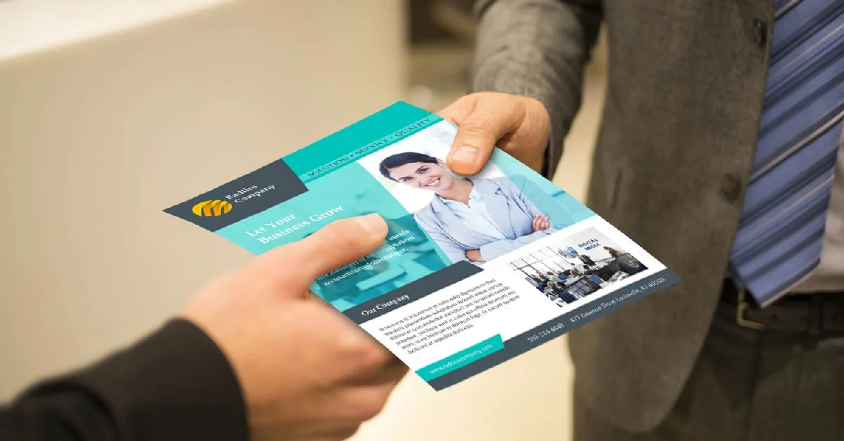 Two professionals exchanging a printed business flyer as part of an offline marketing strategy, highlighting how physical promotional materials can help small businesses connect with local customers.